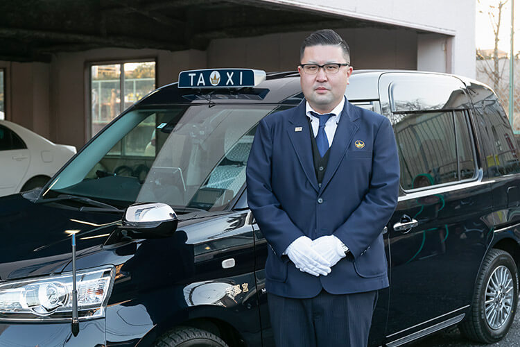 タクシーの前で礼儀正しく立つ男性ドライバー